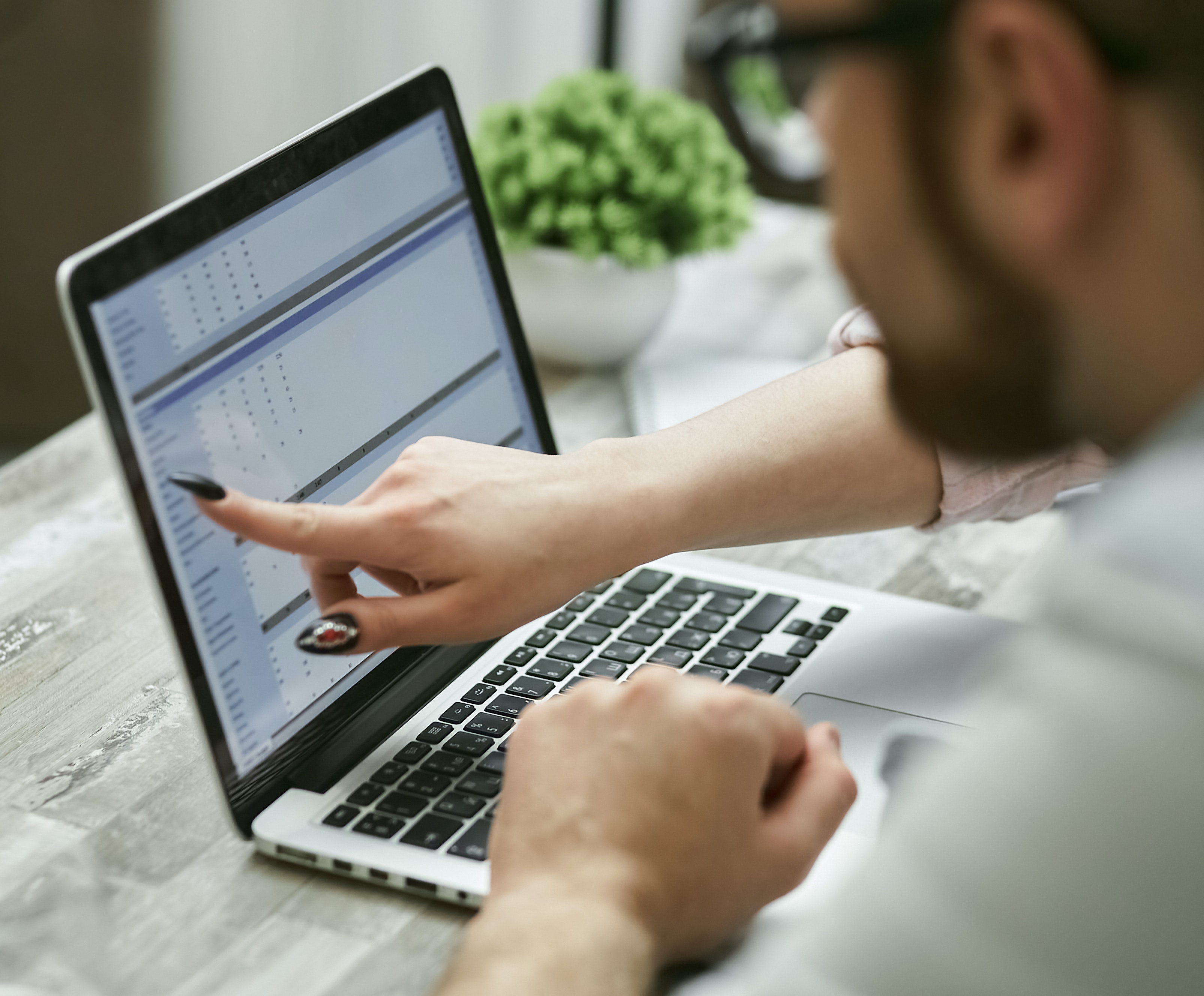 Image of two people looking at a MacBook pointing at the screen.